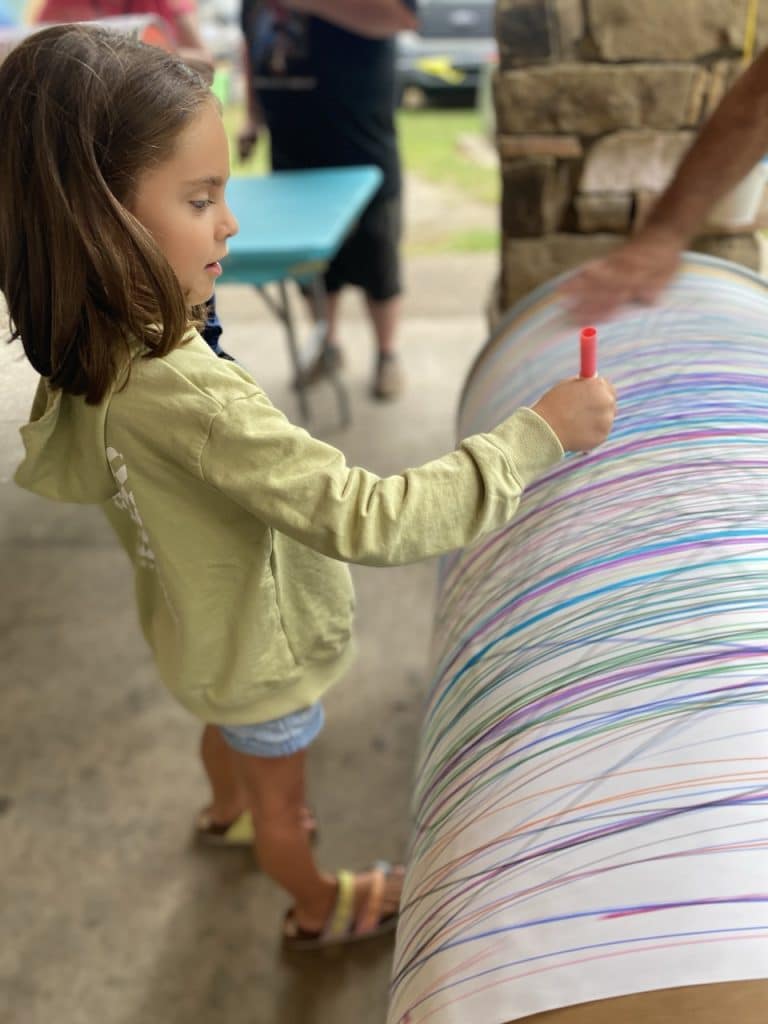 Kids creating collaborative art with a giant spinning art barrel