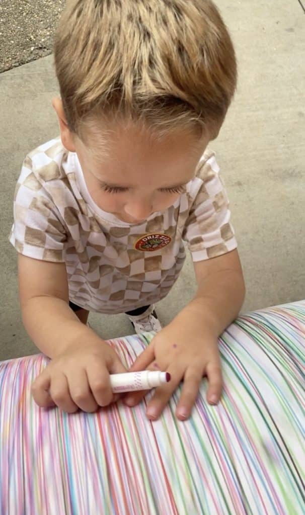 Child drawing with markers while a partner spins the giant art barrel